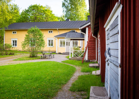 Keltainen puurakennus ja punaisia varastorakennuksia.