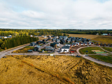 Taloja maiseman keskellä, kuvassa myös metsää ja peltoa tai niittyä