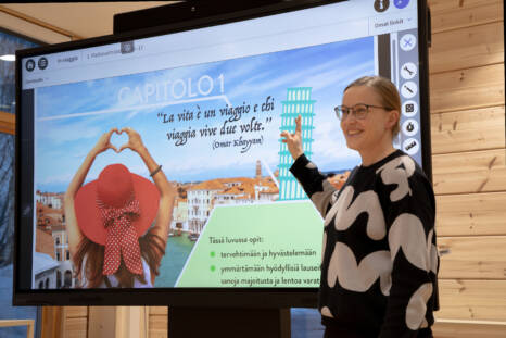 Opettaja valkokankaan edessä opettamassa vierasta kieltä