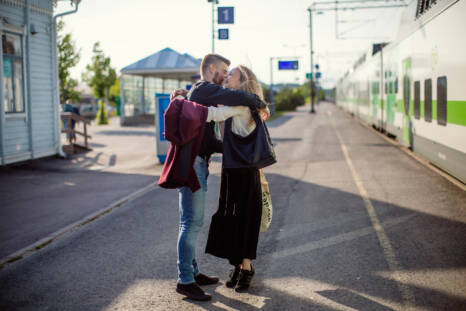 Nainen ja mies halaavat juna-asemalla, taustalla juna