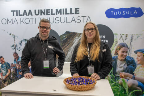 Kaksi kunnan työntekijää OMAKOTI-messuilla esittelypöydän takana