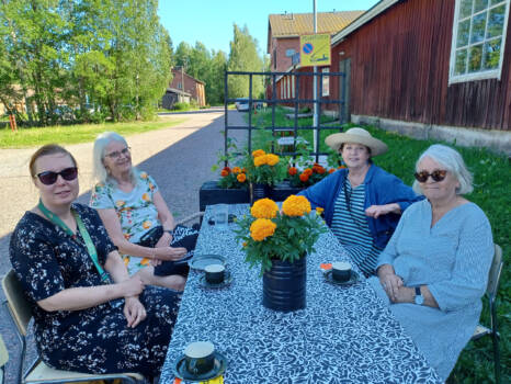 Neljä henkilöä istuu kahvipöydän äärellä