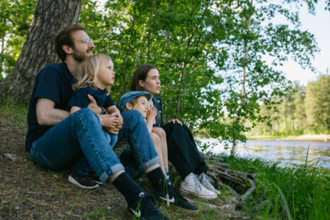 Kaksi lasta ja kaksi aikuista istuvat rannassa