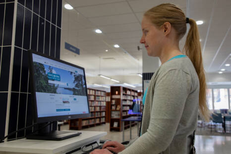 Henkilö kirjaston tietokoneen edessä