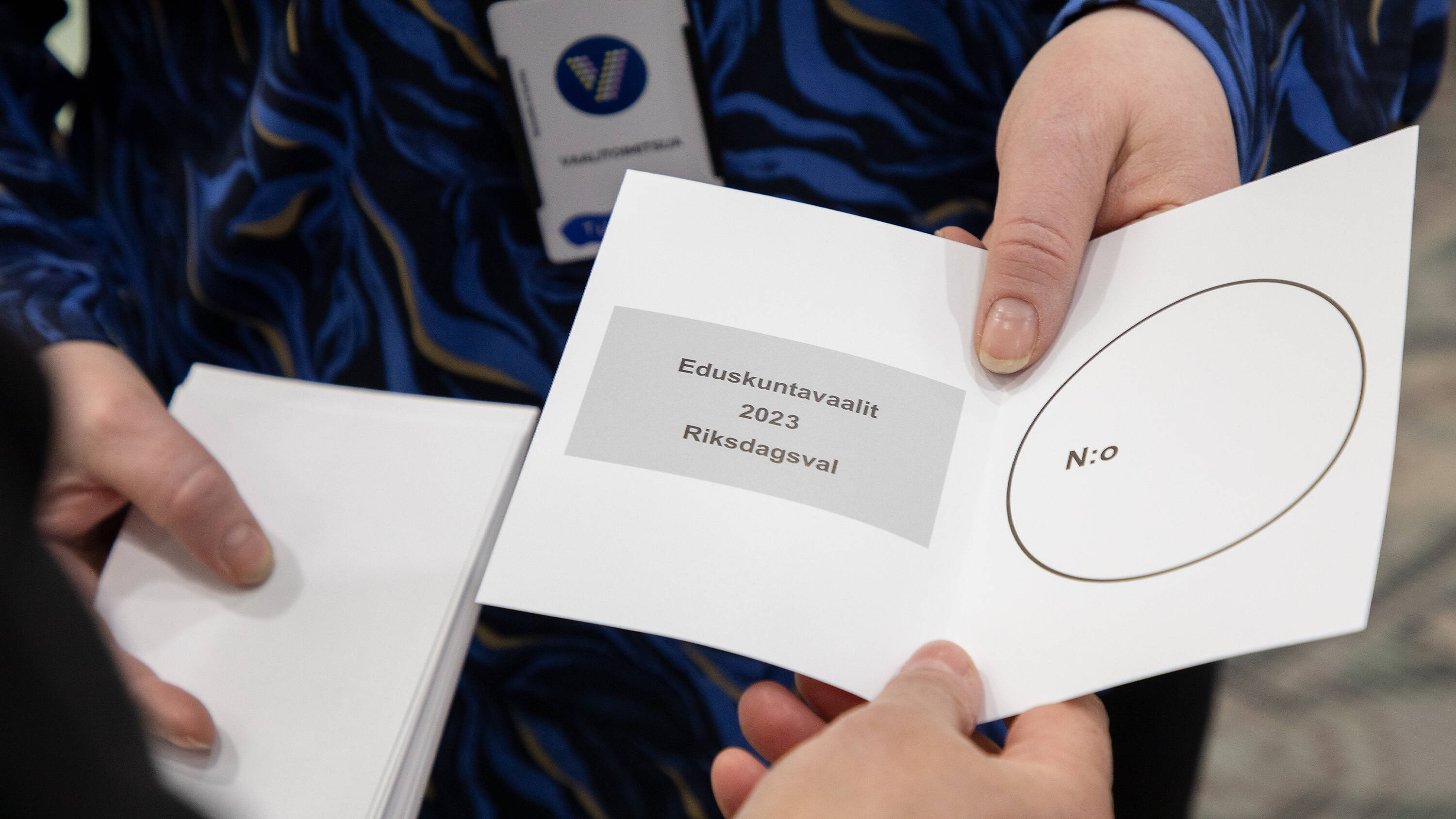 Vaalitoimitsija ojentaa äänestyslipun äänestäjälle