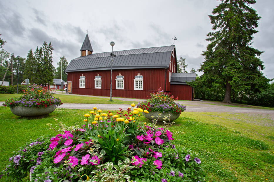 Kellokosken kirkko ulkoapäin kuvattuna. Edustalla on kesäkukkia.