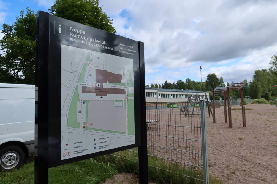 Kuva opastekyltistä, jossa kerrotaan rakennuksen sijainti ja kulkutiet
